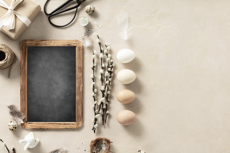 Easter composition with vintage Easter decorations and chalk board on beige stone backgroundの写真素材