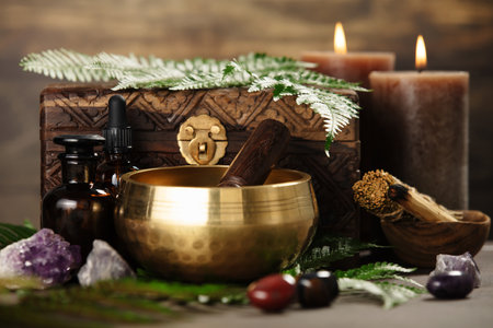 A golden singing bowl with a wooden striker, crystals, and candles arranged for spiritual or meditation purposes.の写真素材