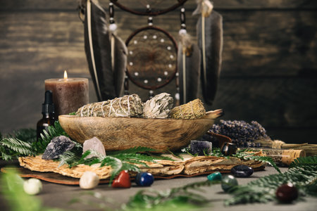 A serene arrangement of sage bundles, crystals, and ferns in a wooden bowl, with a lit candle and dreamcatcher adding to the spiritual ambiance.の写真素材