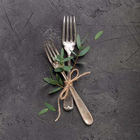 A cohesive series of creative flat-lay compositions featuring vintage silverware on a dark textured stone backdrop.の写真素材