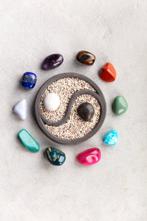 A small yin yang zen garden with sand and contrasting black and white stones in the center,...