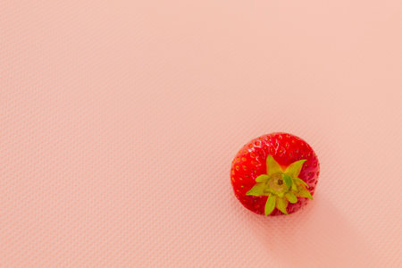 One fresh homemade strawberry on a pink backgroundの写真素材
