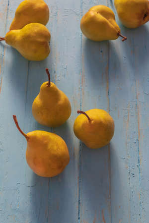 In a vertical photo of a pear. They are on a wooden table, which has long been painted blue. Pears are clean.の写真素材