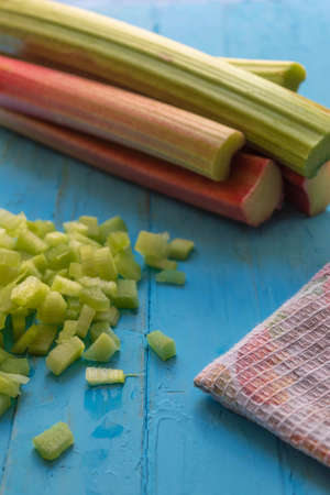 The home rhubarb lies on a blue wooden table, next to a towelの写真素材
