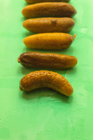 The vertical photo shows pickles, which have two colors: yellowish and green. Cucumbers lie in a row, one by one.の写真素材