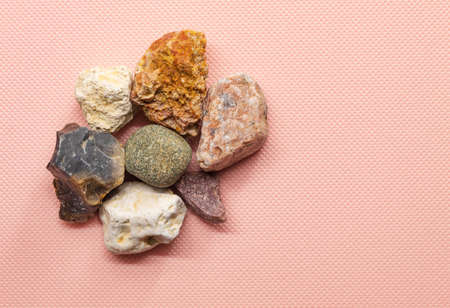 In the horizontal photo on the pink background is a small number of stones. They are of different colors, shapes. Stones from the streetの写真素材