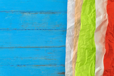 On a blue wooden table lies a colored crumpled paper