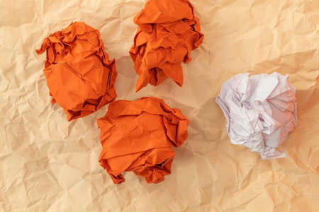 Three red crumpled paper and one white paper lie on an orange slightly crumpled sheet of paperの写真素材
