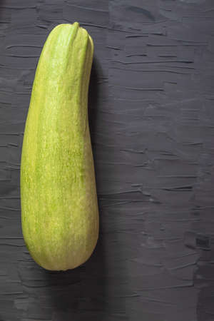 View from above on a large fresh courgette that lies on a gray backgroundの写真素材