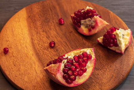 On a wooden board of round shape lies a fresh and juicy pomegranateの写真素材