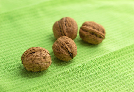 Four whole walnuts lie on a green kitchen towel