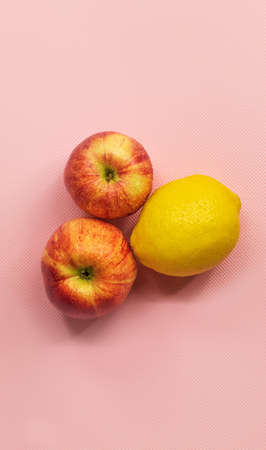 On a pink background in the center are two ripe apples and one yellow lemonの写真素材