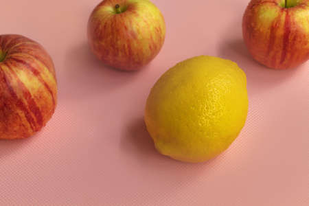 Fresh and ripe three gala apples with lemon in the center on a pink backgroundの写真素材