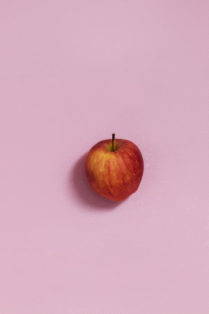 The vertical photo shows a picture of food. This apple is red in color. One apple. The apple is whole and in the skinの写真素材