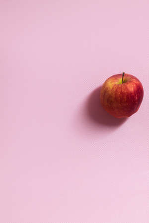 The vertical photo shows a picture of food. This apple is red in color. One apple. The apple is whole and in the skinの写真素材