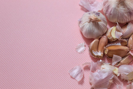 The photo shows purple garlic. Garlic lies on a pink background. Two heads of garlic whole and with...