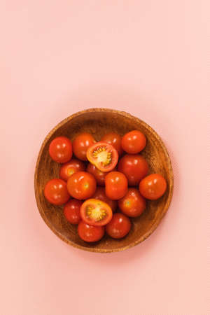 The photo shows a picture of healthy and delicious food. These are red cherry tomatoes. They are small and fresh in a wooden plate.の写真素材