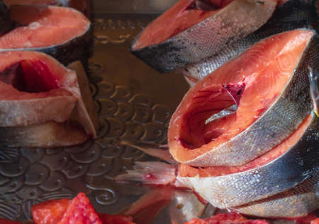 The photo shows a picture of food. Close-up of pieces of red fish lying on top of each other on a tray. Raw fish, cut into large piecesの写真素材