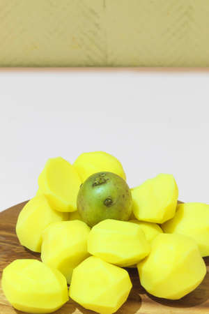 A photo with a pink background has an image of food. Here is a product of the same type: raw potatoes. Whole potatoes, thoroughly washed with water. The potatoes are on the boardの写真素材