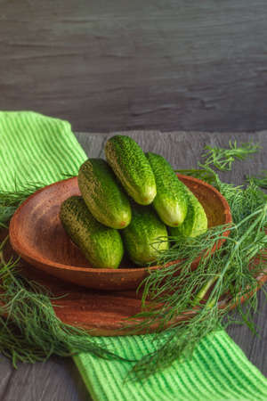 The photo shows an image of healthy food. These are raw green cucumbers in a wooden plate with dillの写真素材