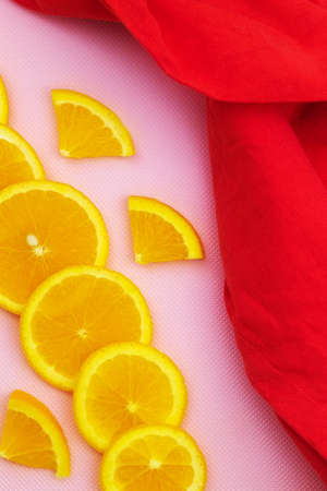 Juicy and fresh orange slices lie on a pink background with a red clothの写真素材