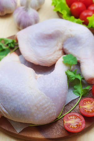 Close-up of raw chicken meat, next to tomatoes, herbs and garlicの写真素材