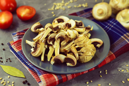 On a kitchen towel on a plate there are raw chopped mushrooms for making soupの写真素材