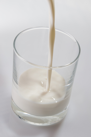 Milk pouring into the glassの写真素材