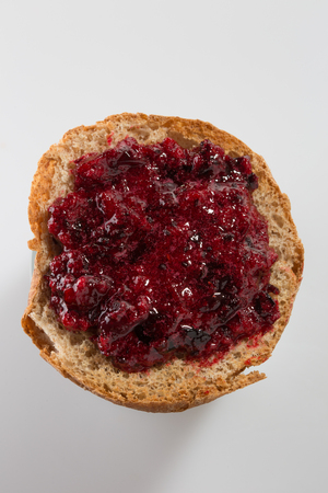 Roasted bread with layer of black currant jam on white backgroundの写真素材