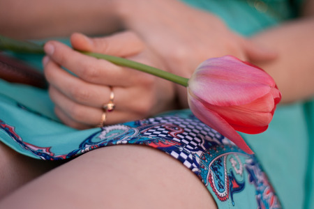 Pink tulip in the left woman hand. Girl in green dress holding a flower.の写真素材