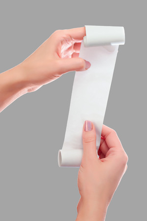 Woman or Girl Hold in Hands Roll of Paper With Printed Receipt Mock Up Template. Clean Mockup. May be Placed in Article About Shopping, Paying Bills, Finance. Copy Space & Clipping Path. On Grayの写真素材