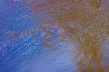 Reflection of a blue sky in a creek with thawed water in the spring April forest at sunset