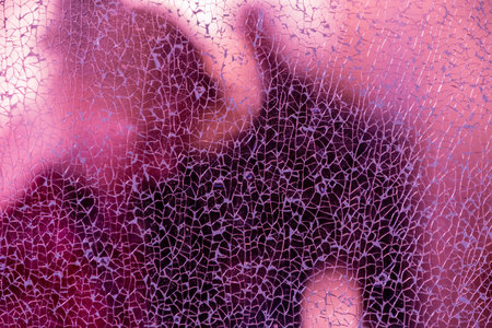Blurred silhouettes of people behind broken glass. Fine mesh of cracks. Creative background. Female...