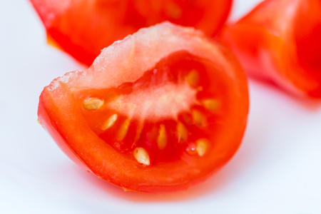 A fresh sliced tomato on white background. Vegetarian salad. Healthy diet food. Closeup. Side view.の写真素材