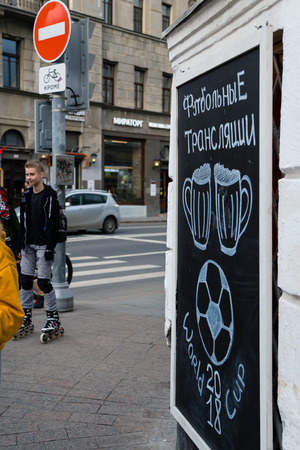 MOSCOW, RUSSIA - APRIL 30, 2018: People near the chalkboard on Solyansky proezd with the advertisement of football broadcasts of the World Football Championship mundialia FIFA 2018. Beer sports bar.のeditorial素材