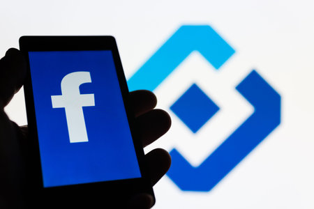 MOSCOW, RUSSIA - MAY 9, 2018: Smartphone in hand with logo of popular social network Facebook....