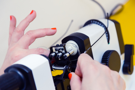 The ophthalmologist determines the optical power of the spectacle lenses and the lens centers on the optical stand. Glasses in female hands with manicure. Doctor's office. Optics store.の写真素材