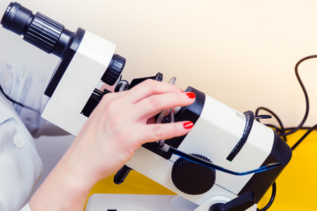 The ophthalmologist determines the optical power of the spectacle lenses and the lens centers on the optical stand. Glasses in female hands with manicure. Doctor's office. Optics store.の写真素材