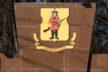 MOSCOW, RUSSIA - APRIL 9, 2018: The coat of arms of the Lefortovo district on a red marble slab at the entrance to Lefortovo Park in Moscow. In the center there is an image of a soldier of the Lefortovo regiment with a black fusey at the ready and a swordのeditorial素材
