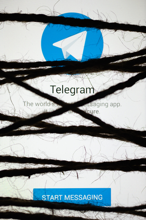 MOSCOW, RUSSIA - September 14, 2018: Smartphone in the dark, tightly wrapped and tied with coarse jute rope bondage lies with glowing screen with popular Telegram messaging app. Concept of censorshipのeditorial素材