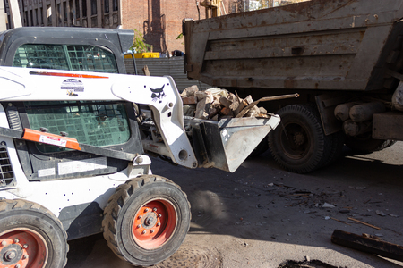 DNIPRO, UKRAINE - NOVEMBER 1, 2018: Special machinery in a bucket transports debris to be loaded into a dump truck near a construction siteのeditorial素材