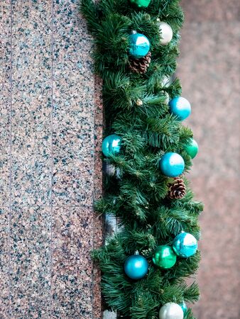 Christmas toys close-up on the branches of green plastic spruce. Macro shot of Christmas tree accessories. Mock up for holiday card background. Copy space on blurred bokehの写真素材