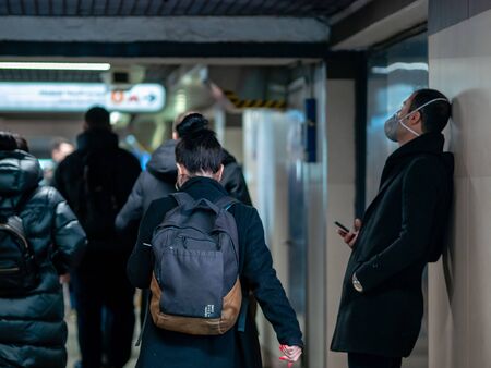 Moscow, Russia - December 6, 2019: Man with N95 class face mask respirator in passage near entrance to the Novye Cheryomushki metro station. Man expects someone in a virus protective mask in underpassのeditorial素材