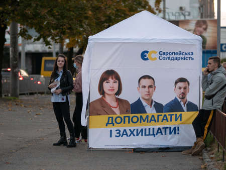 Dnipro, Ukraine - October 23, 2020: Agitators hand out leaflets at campaign cubes ahead of parliamentary elections. Lady with printed promotional materials for European Solidarity party on eve of voteのeditorial素材