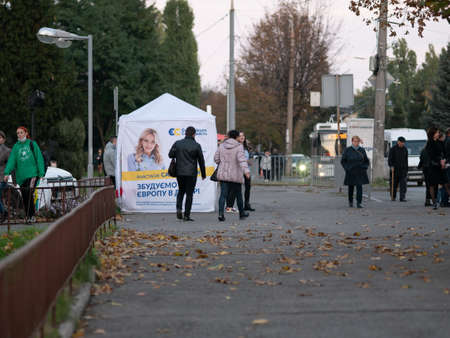 Dnipro, Ukraine - October 23, 2020: Agitators hand out leaflets at campaign cubes ahead of parliamentary elections. Lady with printed promotional materials for European Solidarity party on eve of voteのeditorial素材