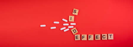 Words side effect on colored red paper texture background. Concept. Pill allergy. Concern of vaccine shot side effect or toxicity. Copy space. Mock up design.の写真素材