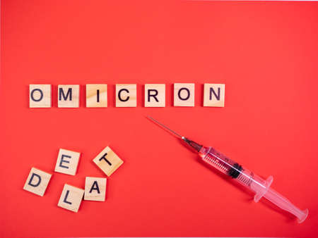 Omicron variant replaces Delta. Emergence of new dangerous strain of coronavirus COVID-19 Omicron. Syringe. Words omicron delta on colored red backgroundの写真素材