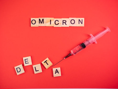 Omicron variant replaces Delta. Emergence of new dangerous strain of coronavirus COVID-19 Omicron. Syringe. Words omicron delta on colored red backgroundの写真素材
