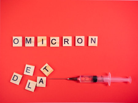 Omicron variant replaces Delta. Emergence of new dangerous strain of coronavirus COVID-19 Omicron. Syringe. Words omicron delta on colored red backgroundの写真素材