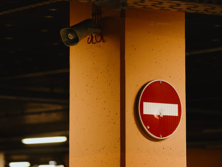 Loudspeaker and prohibition sign on a column in an underground parking lot. Red round sign with a...